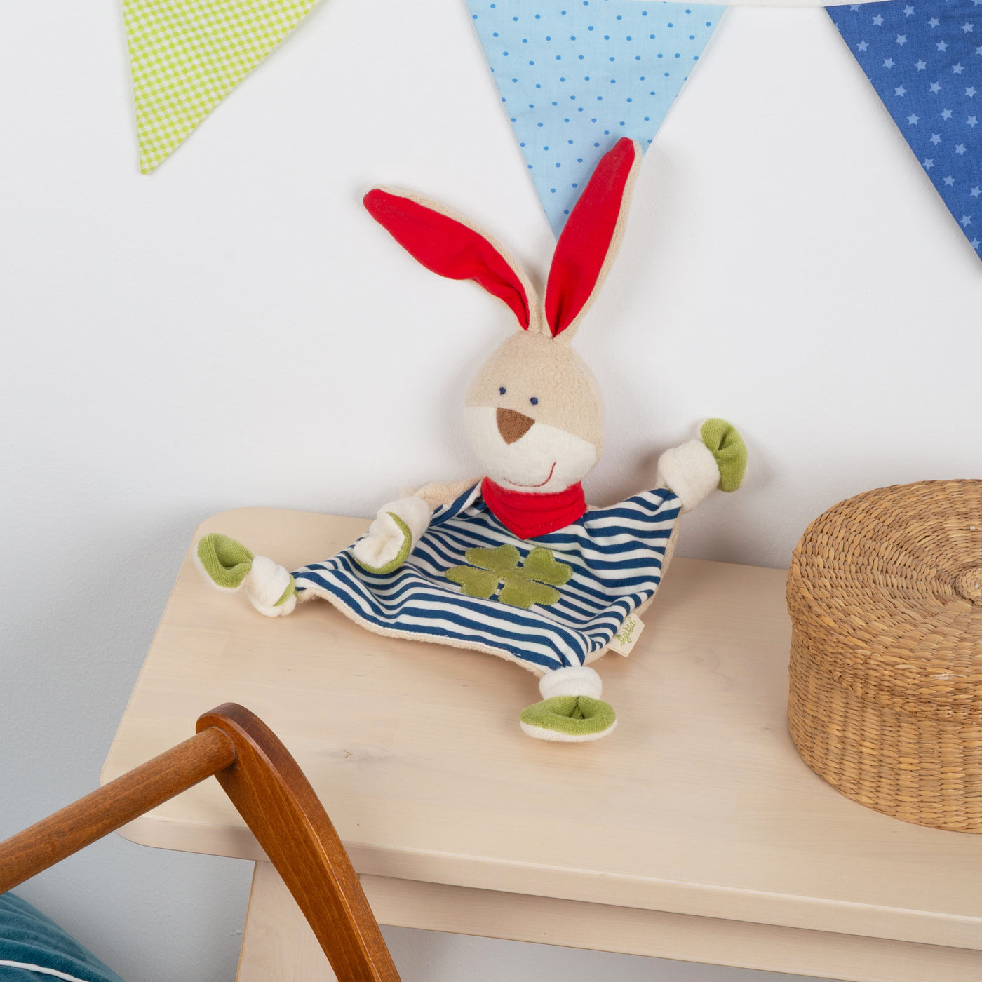 Bio-Schnuffeltuch Hase blau auf einer Bank an die Wand gelehnt