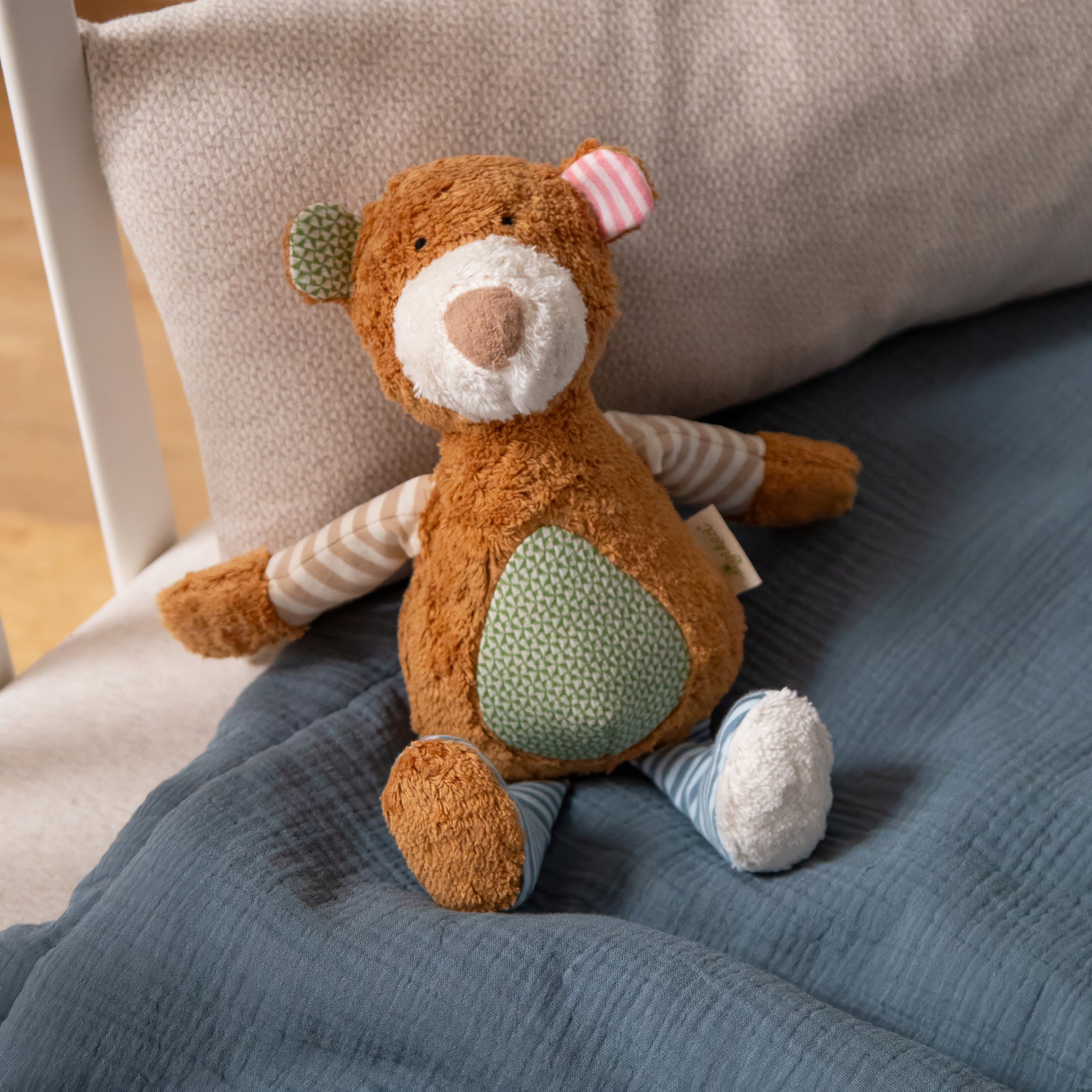 Bär Kuscheltier Pure von Sigikid auf einem Bett sitzend